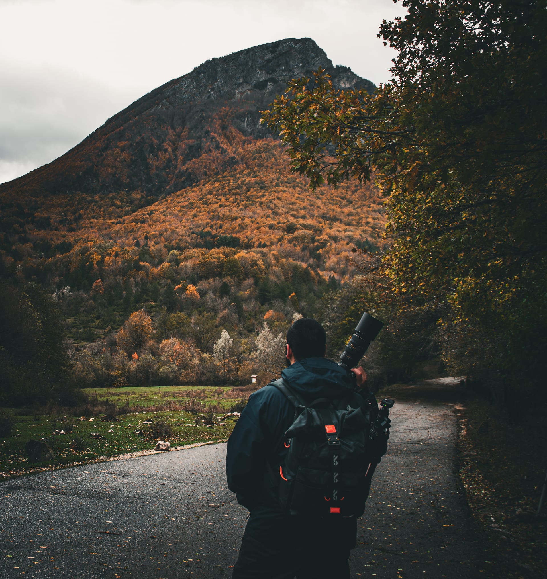 Fotografo di spalle davanti a una montagna autunnale